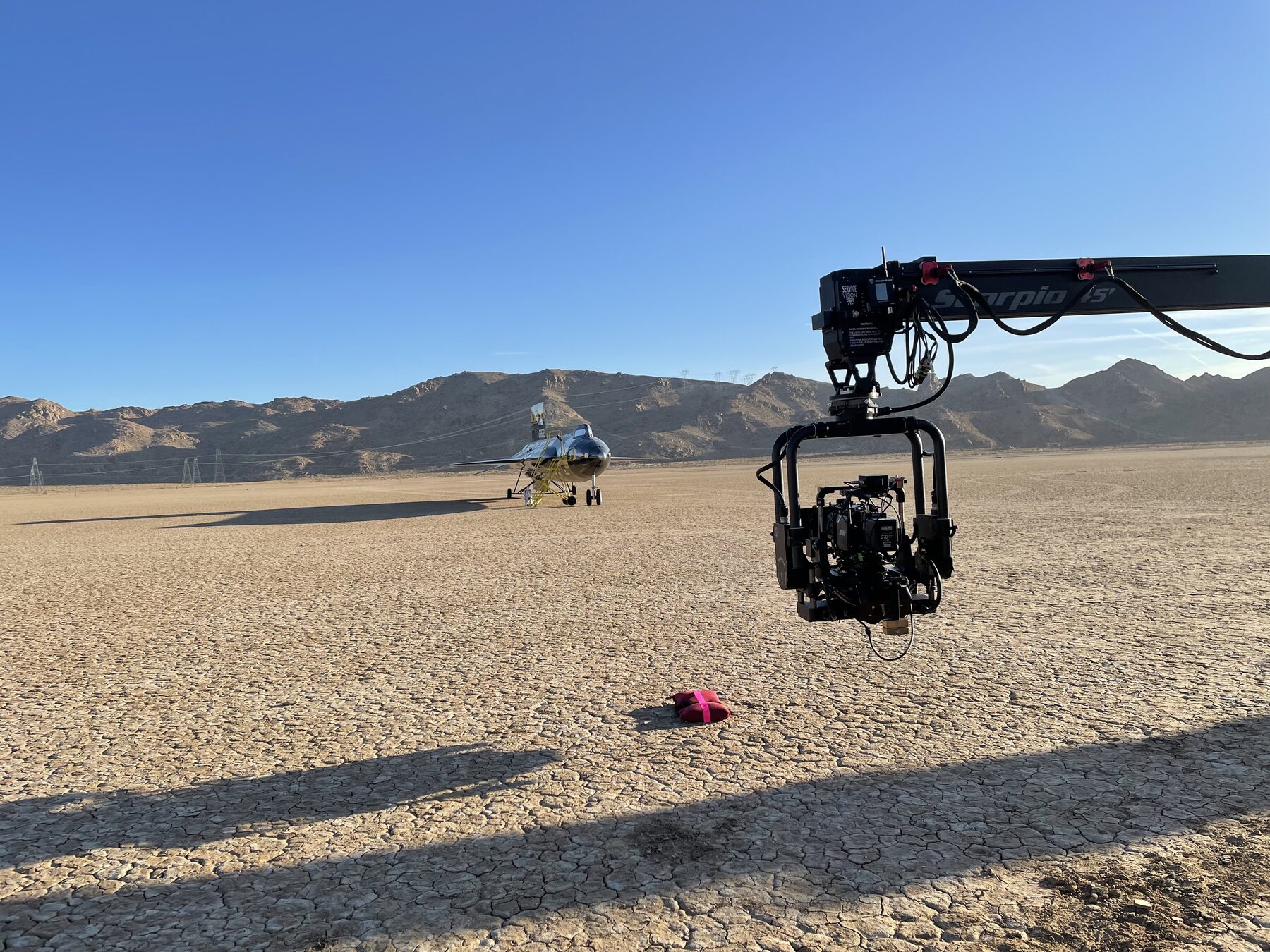 Camera crane on a dry desert lakebed with a jet in the background